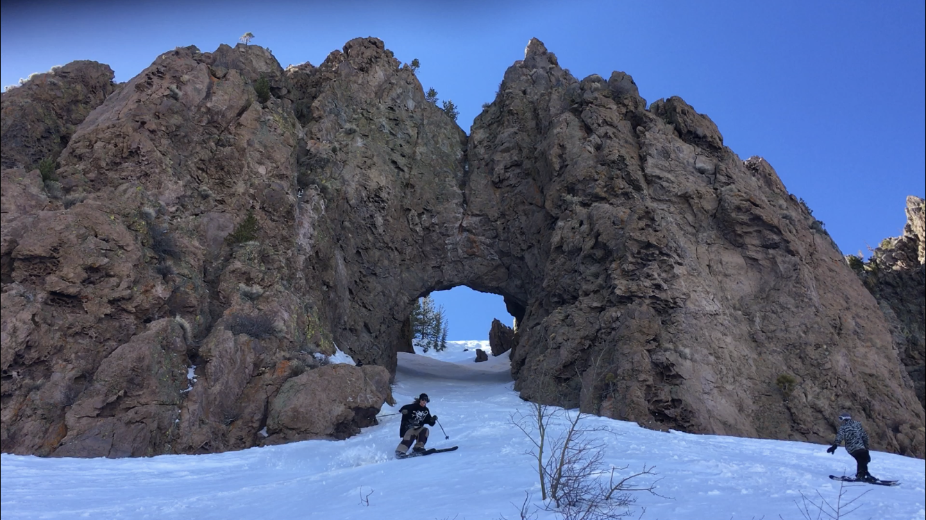 Ryan skiing through a stone cave that arches over the slope of the mountain. 