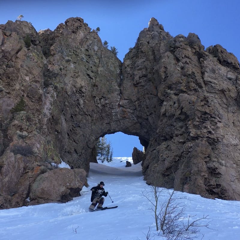 Ryan skiing through a stone cave that arches over the slope of the mountain.
