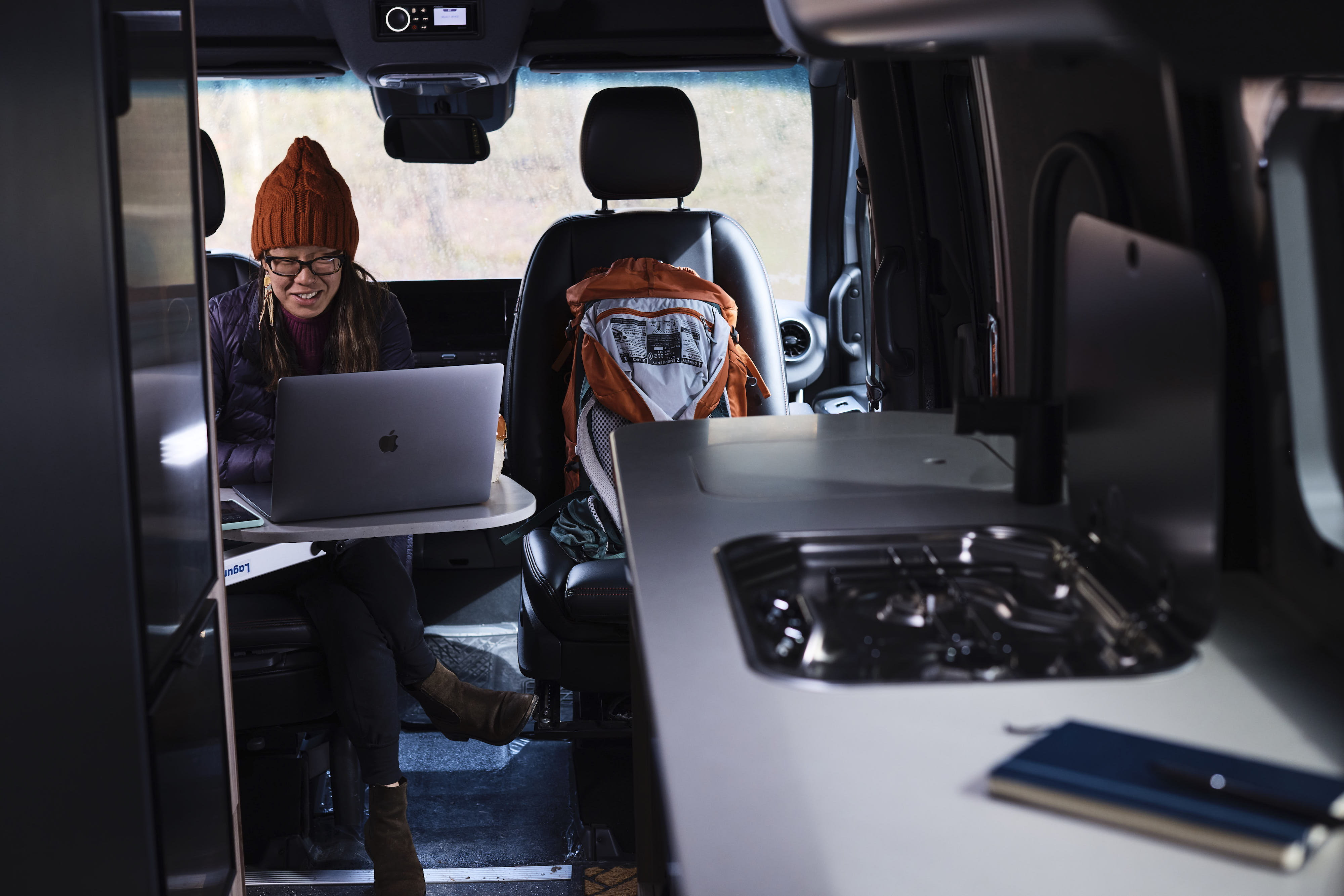 Kathy Karlo working on a laptop inside of an Airstream camper van
