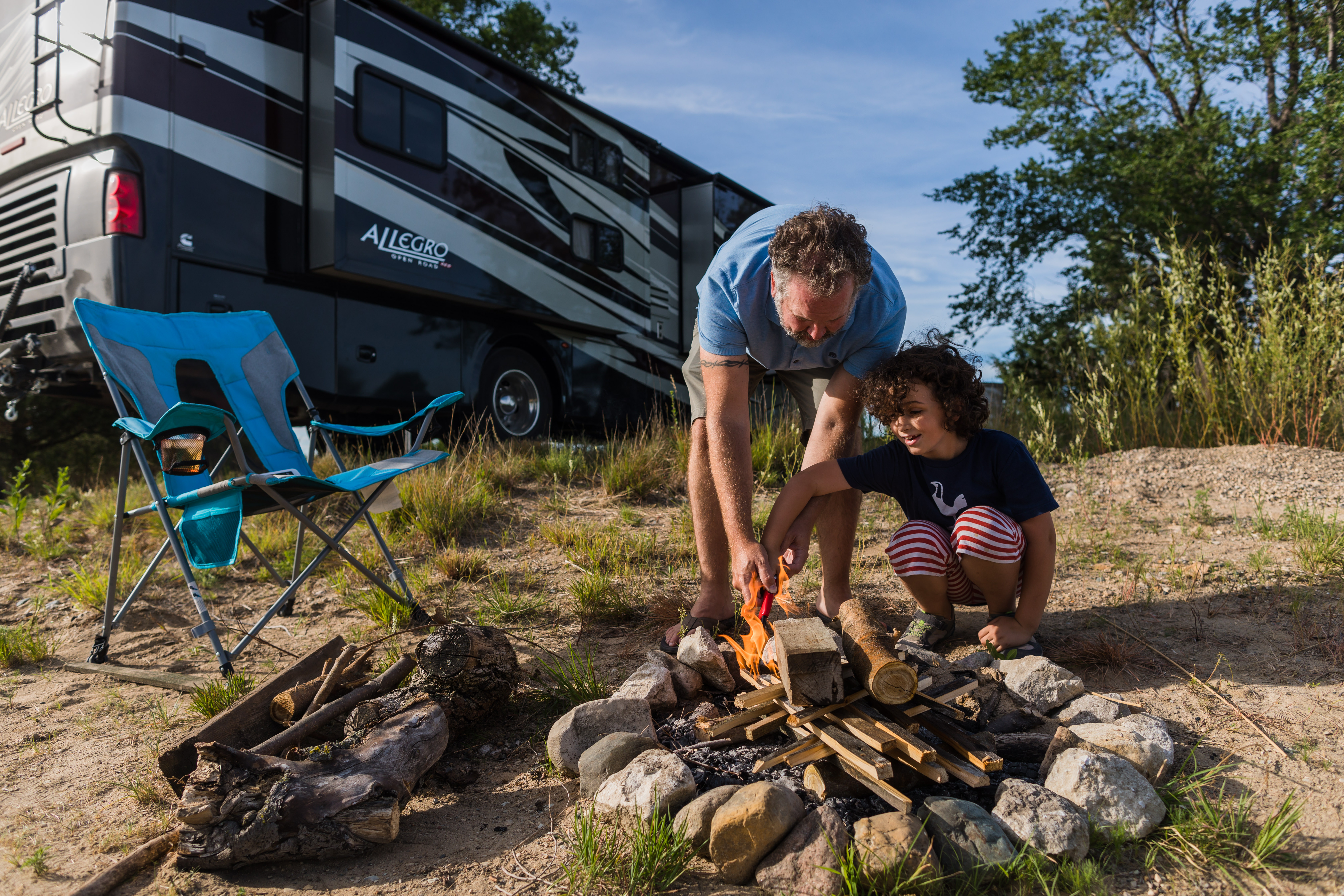 Desiree Walter's son and husband work on building a campfire with their Class A Allegro RV in the background.