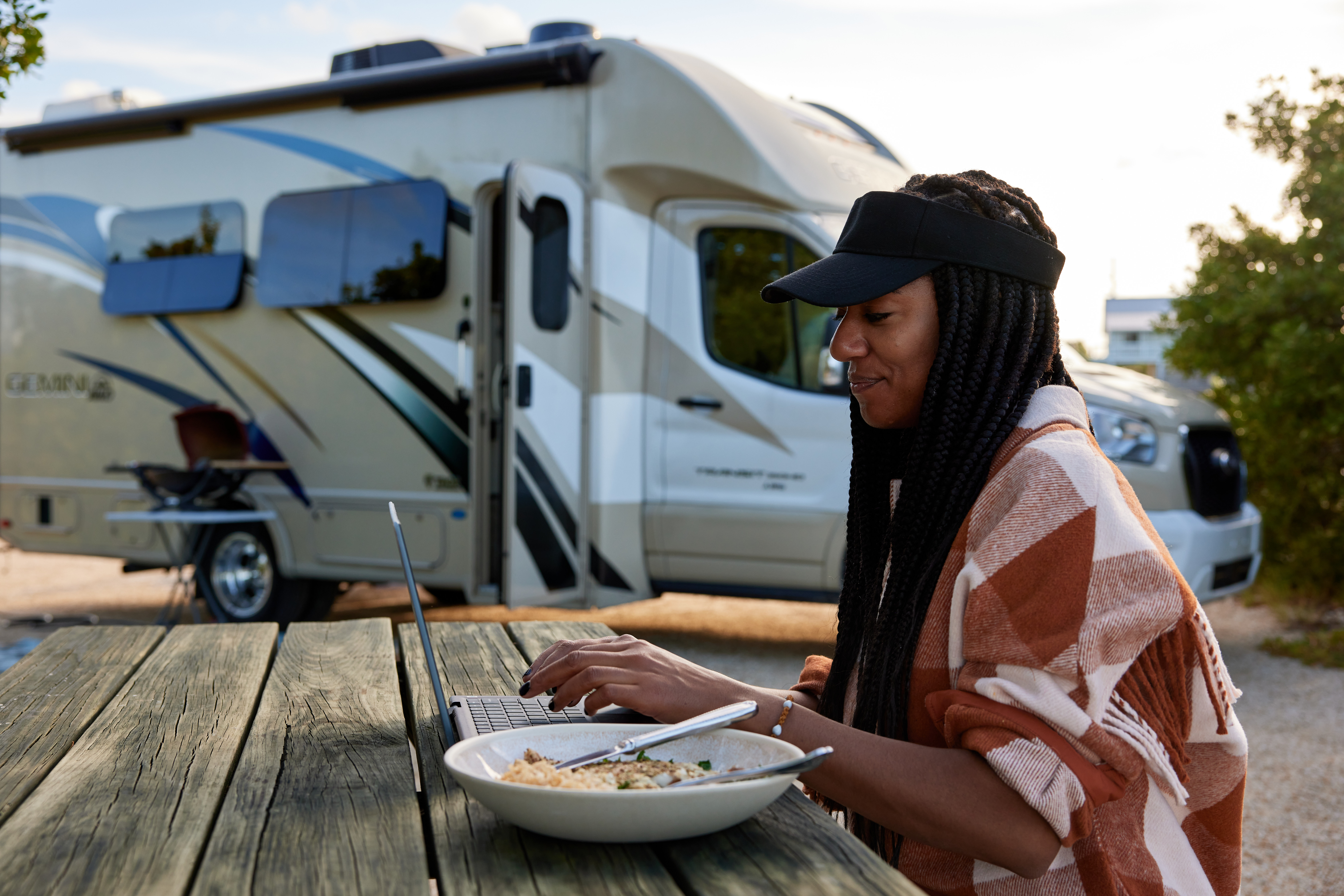 Travel writer Adrienne Jordan eats her dinner and works at a picnic table at Bahia Honda Florida State Park with her Thor Motor Coach Gemini.