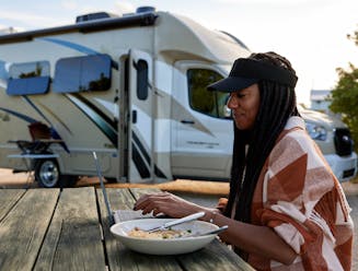 Travel writer Adrienne Jordan eats her dinner and works at a picnic table at Bahia Honda Florida State Park with her Thor Motor Coach Gemini.