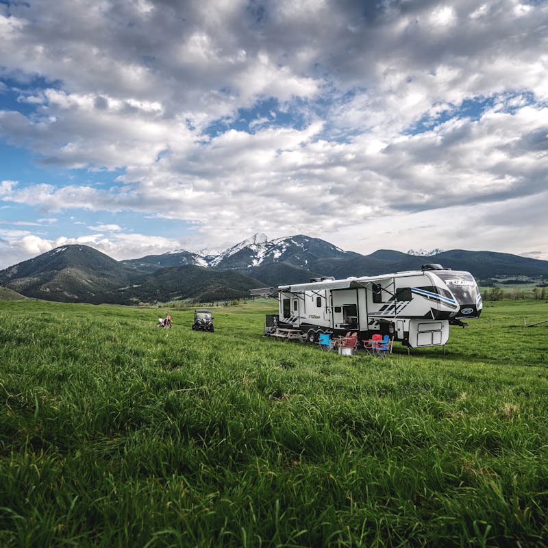 A Keystone RV in a field next to mountains