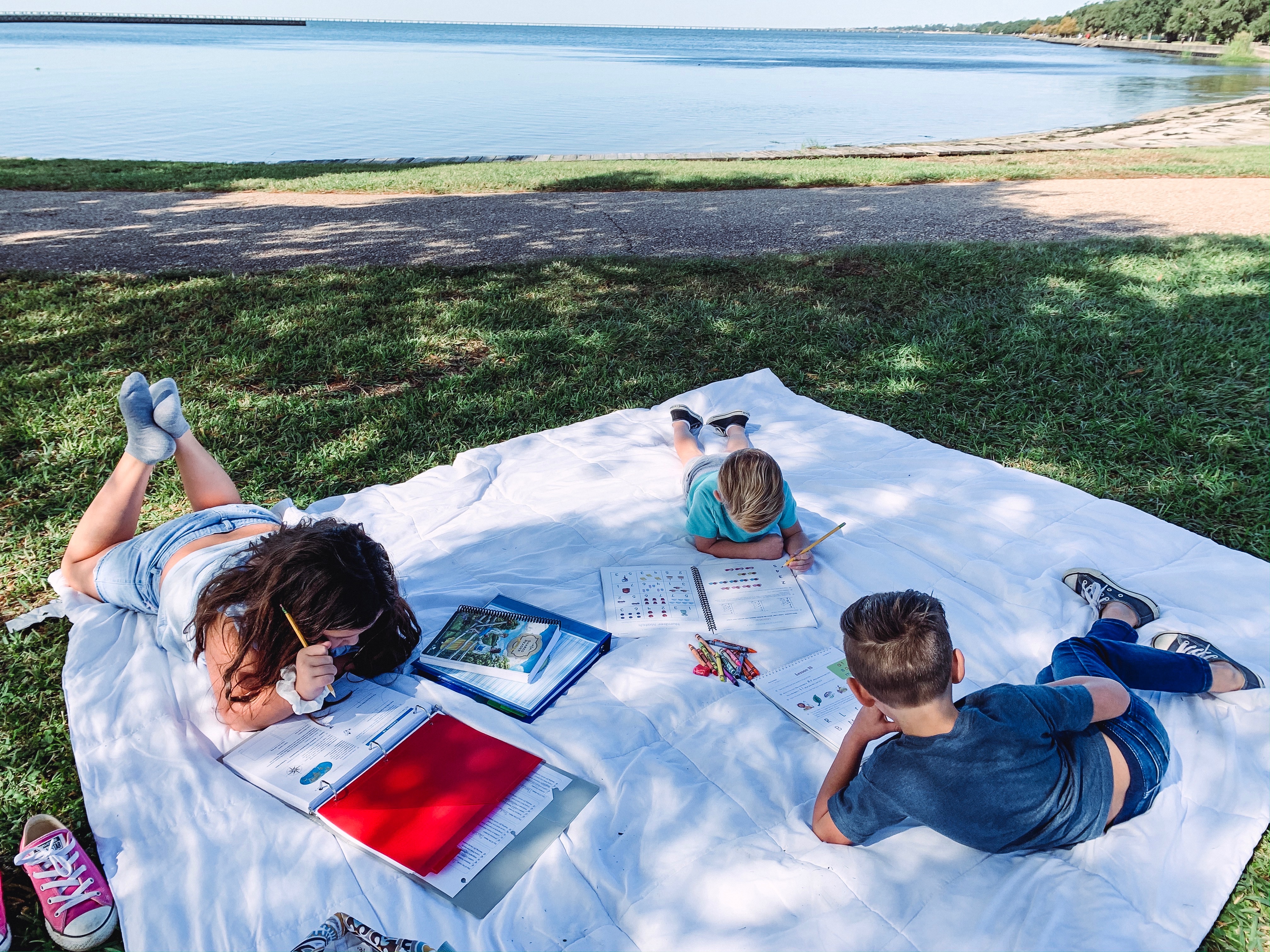 The Darren and Amanda Bone family sits on a blanket outside while reading and studying