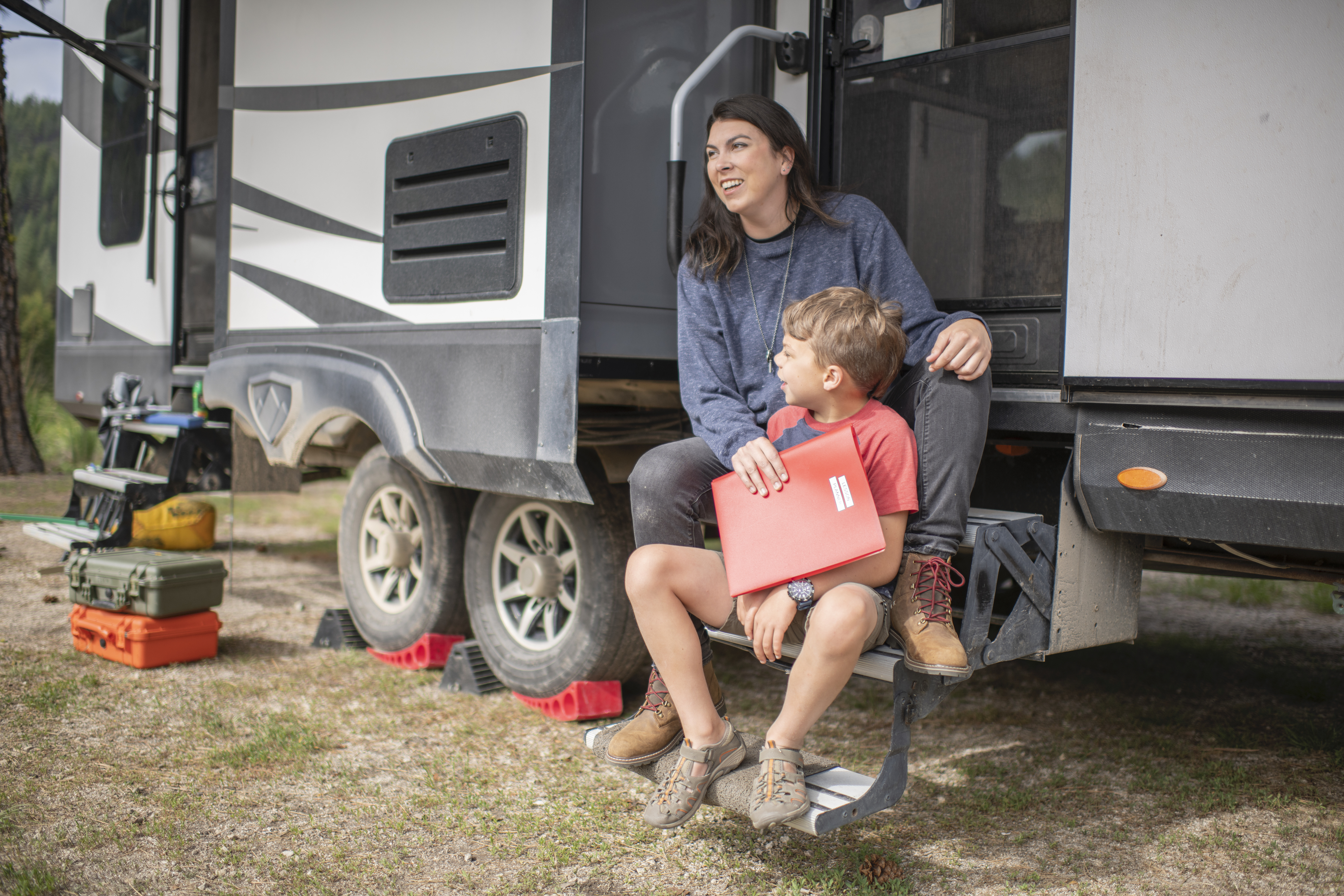Chelsea Day sitting on the steps of her Highland Ridge Highlander with her son.