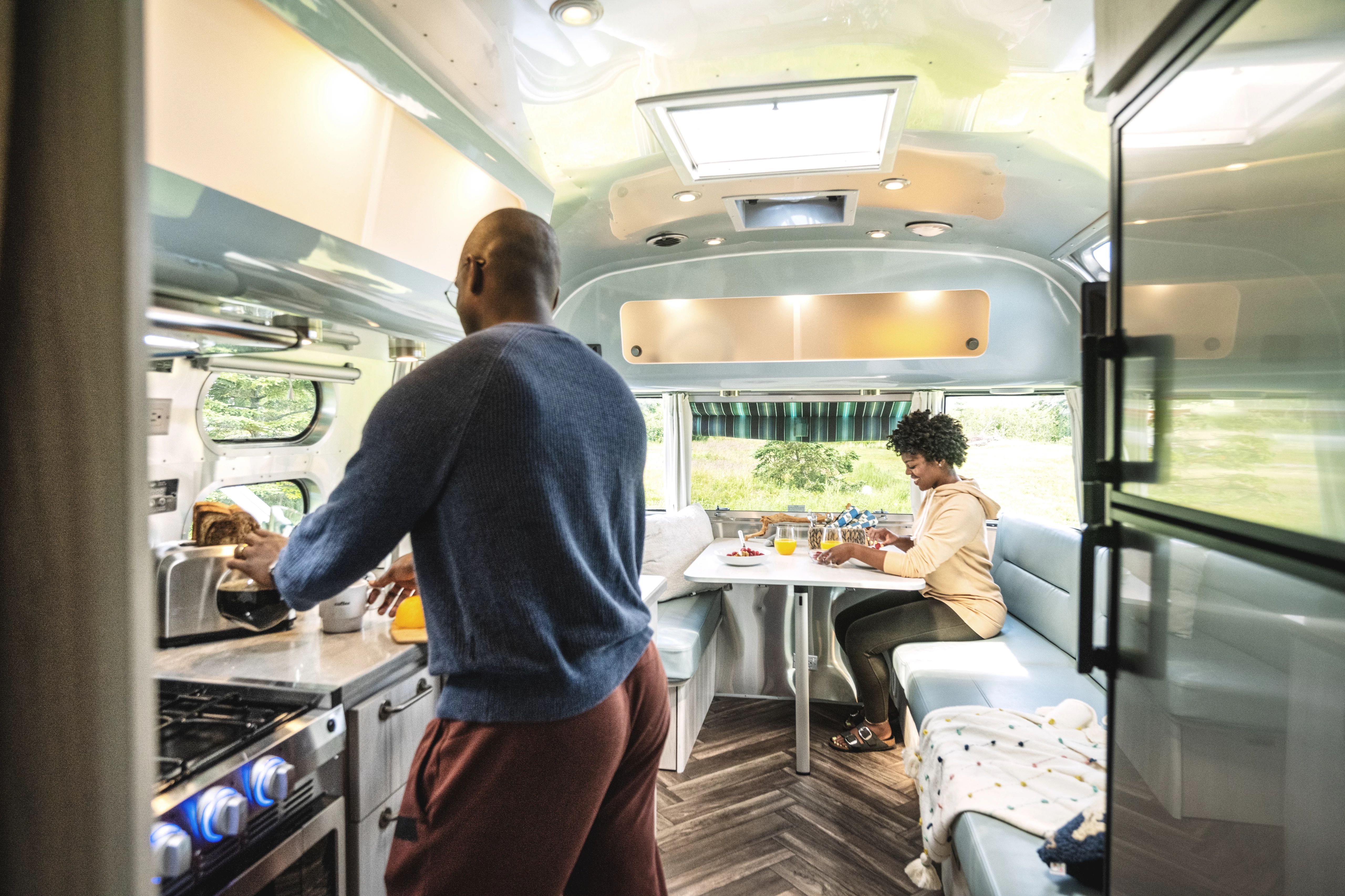 A couple relaxes in the kitchen and dinette are of an Airstream travel trailer
