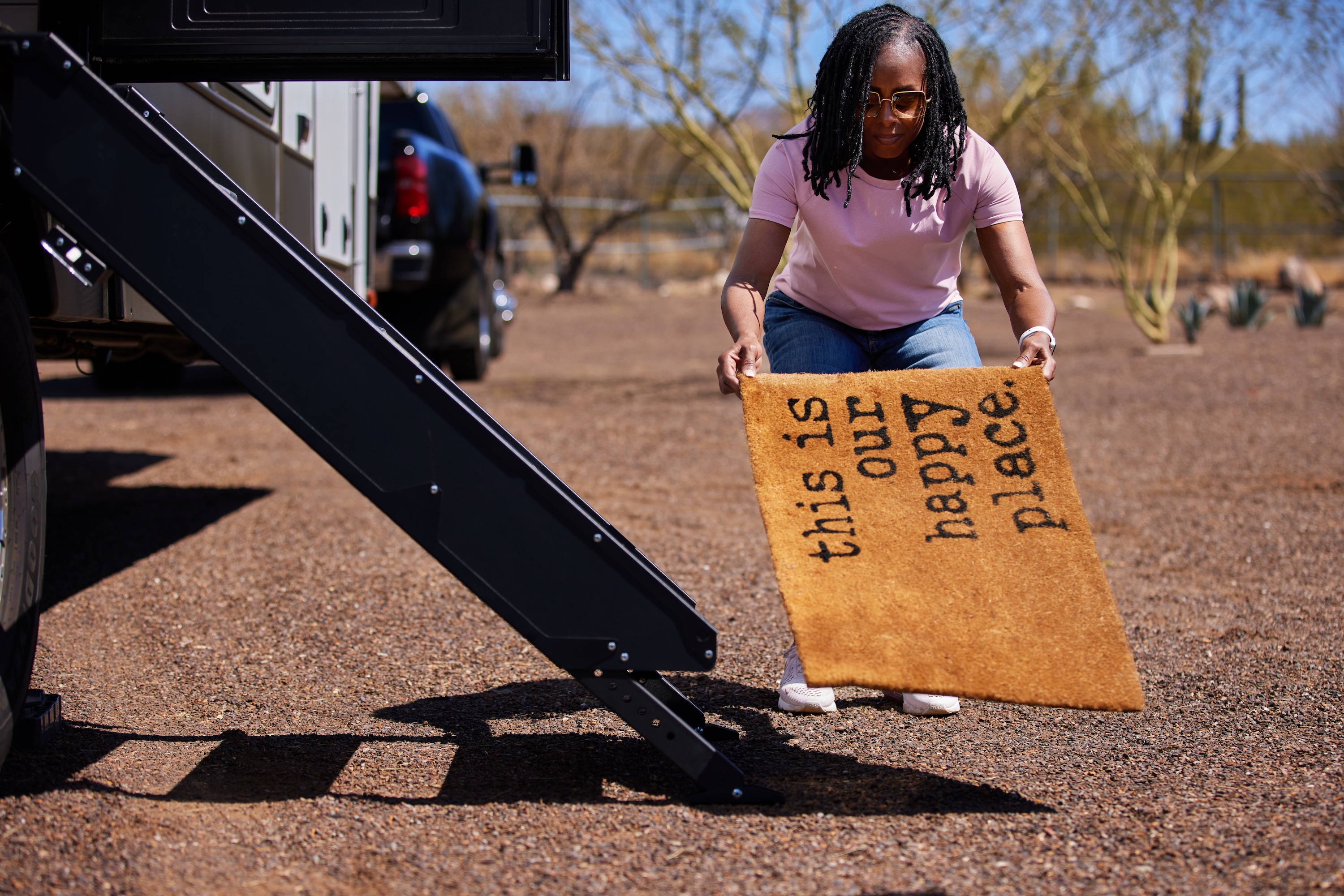 Robin puts out a rug that reads "this is our happy place" by the steps of a Keystone Fuzion.