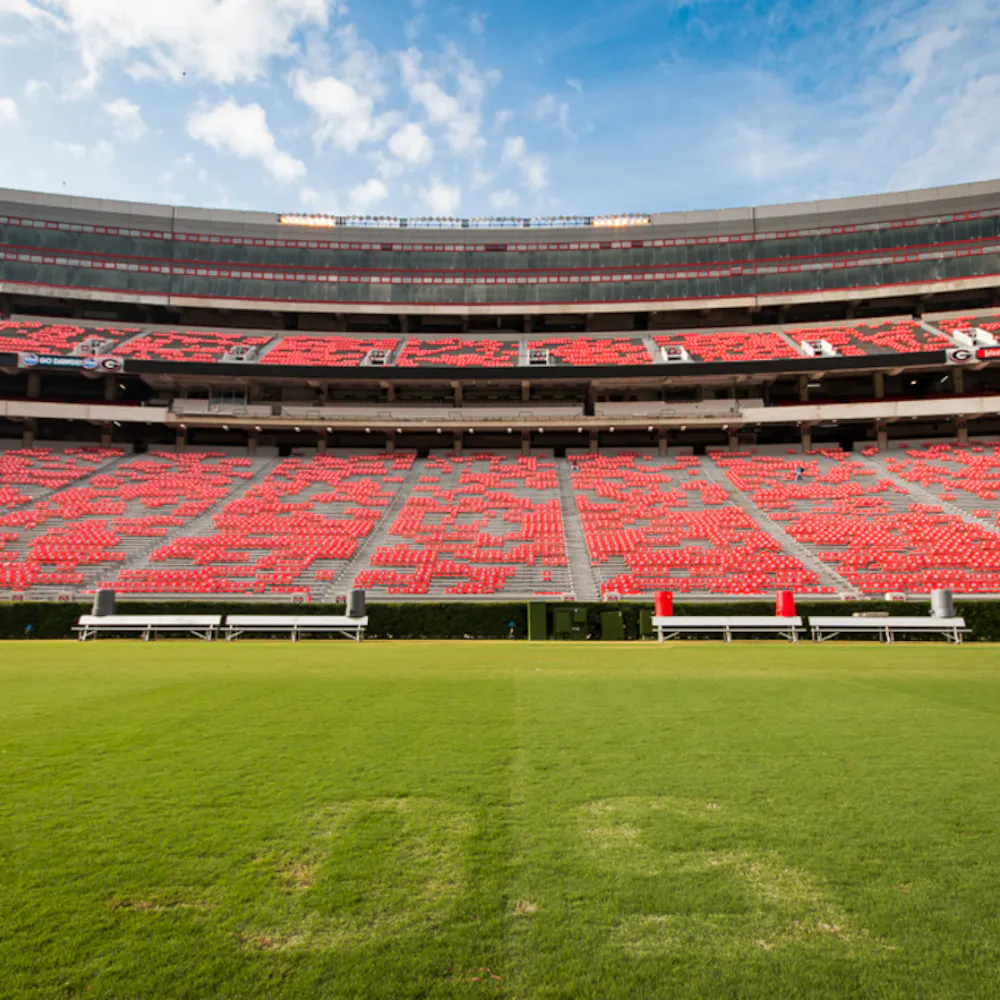 University of Georgia's Sanford Stadium in Athens, Georgia, view from the 50-yard line field, looking up at red seats and box seats.