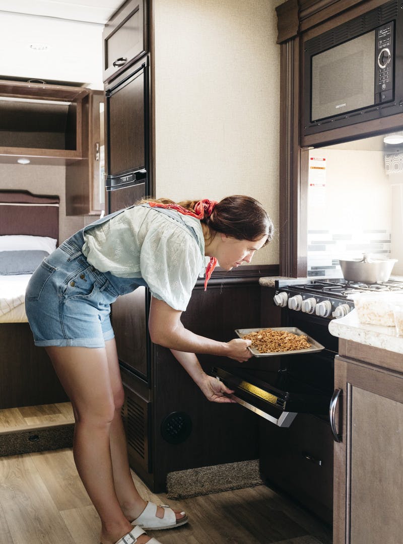 Sarah Glover adding putting the granola into the RV kitchen oven.