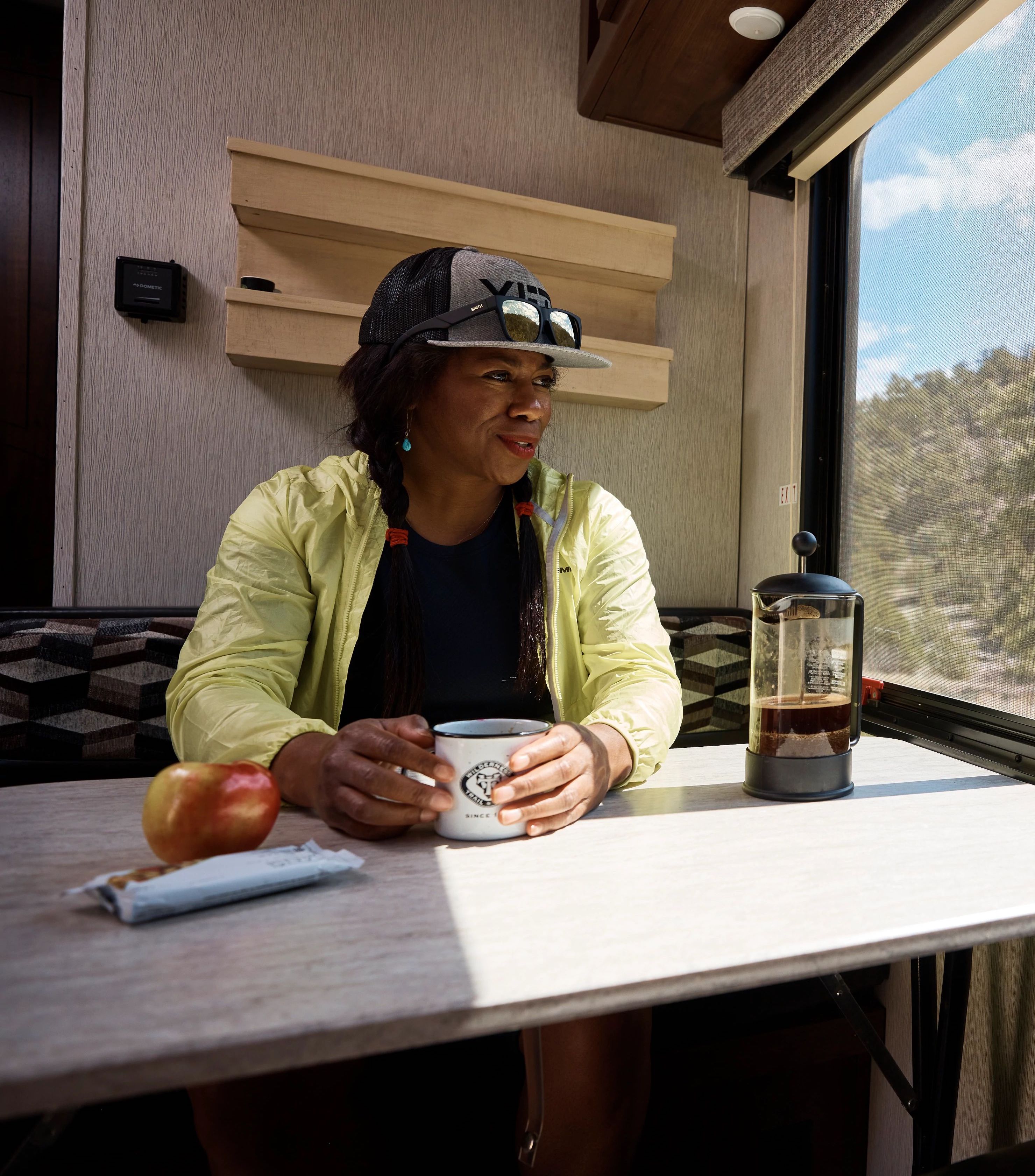 Brooke Goudy sits at an RV dinette table and drinks coffee