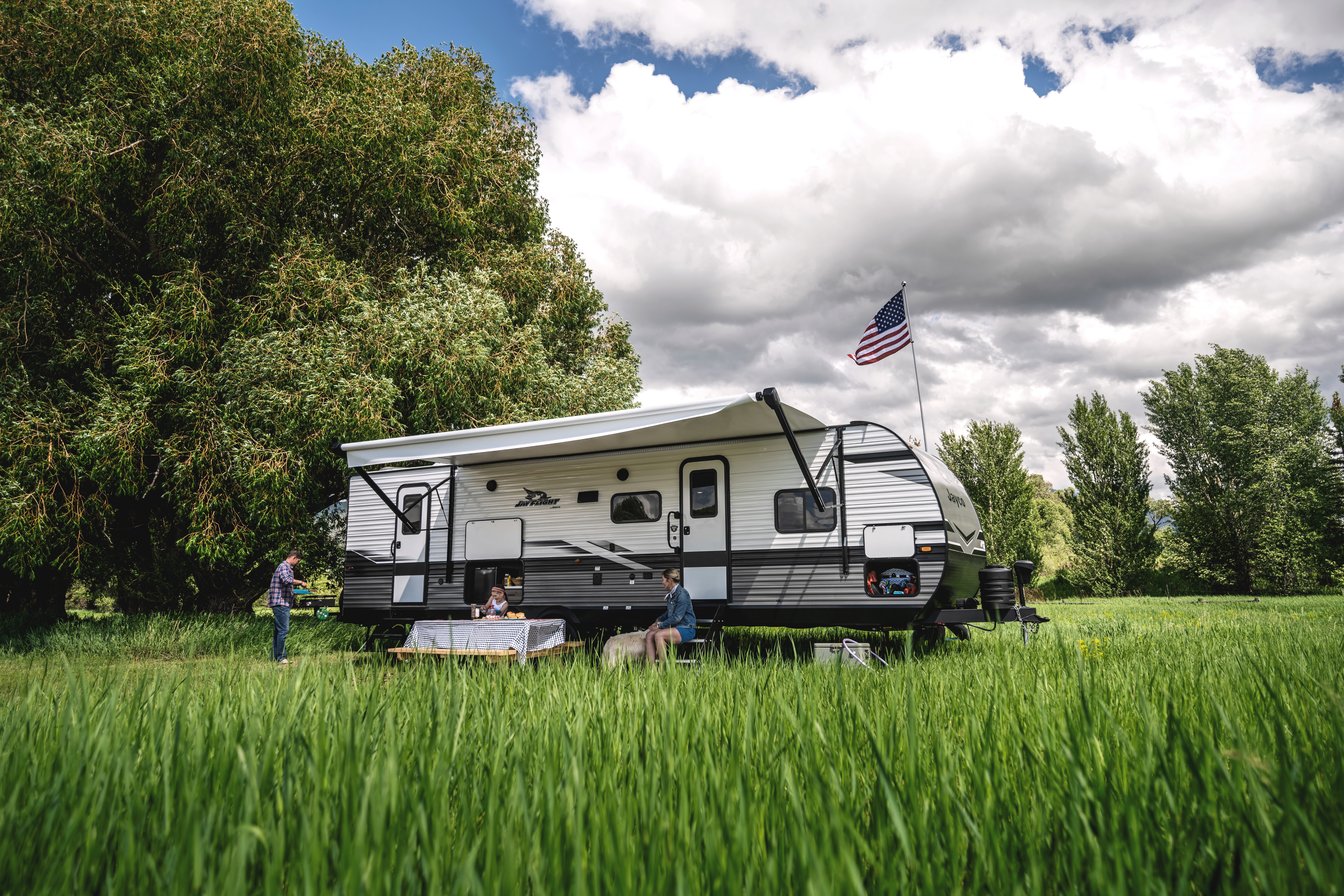A family sits around a picnic table outside of a Jayco Jay Flight.