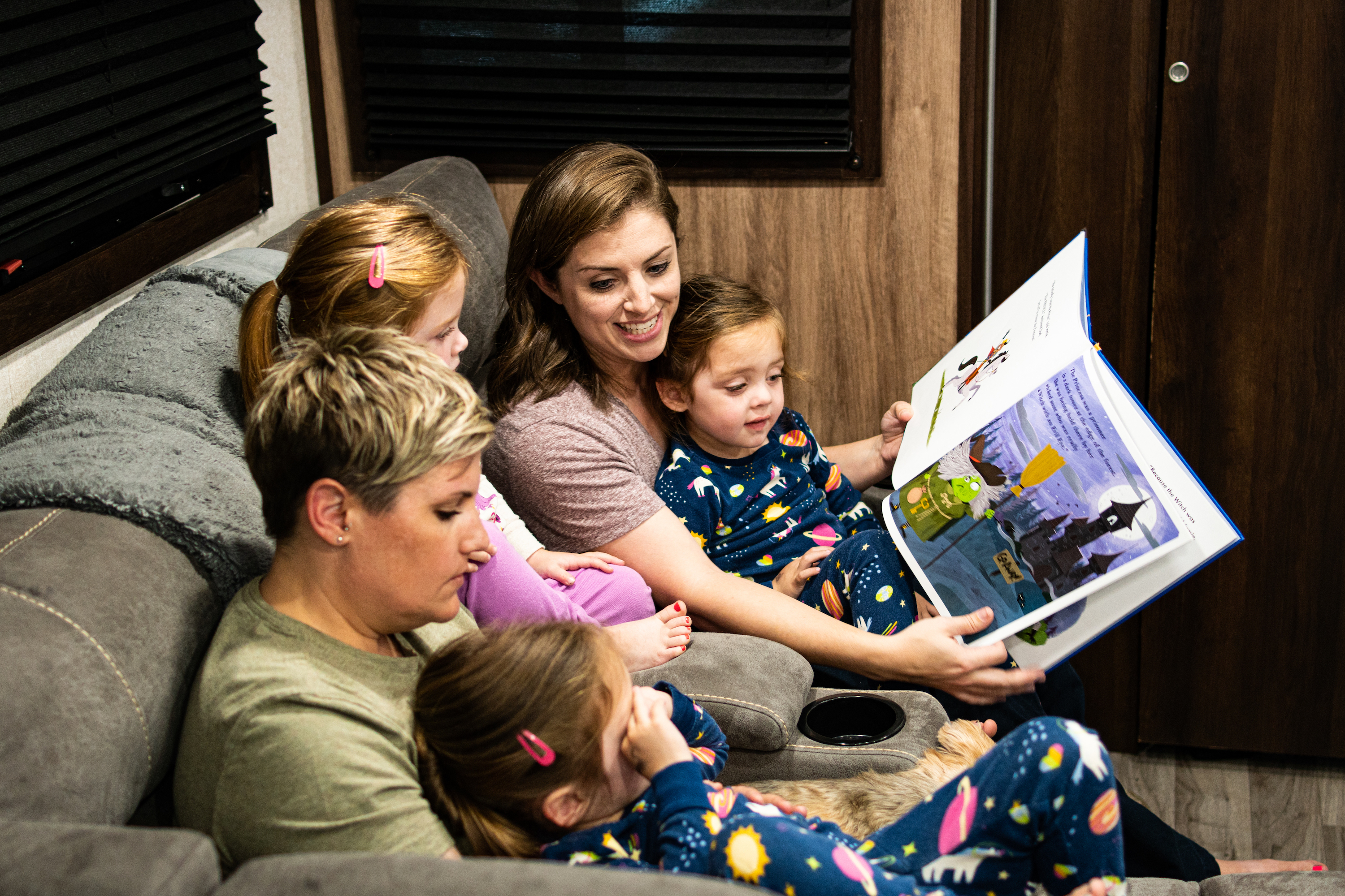 Moms reading to their triplet girls at night.