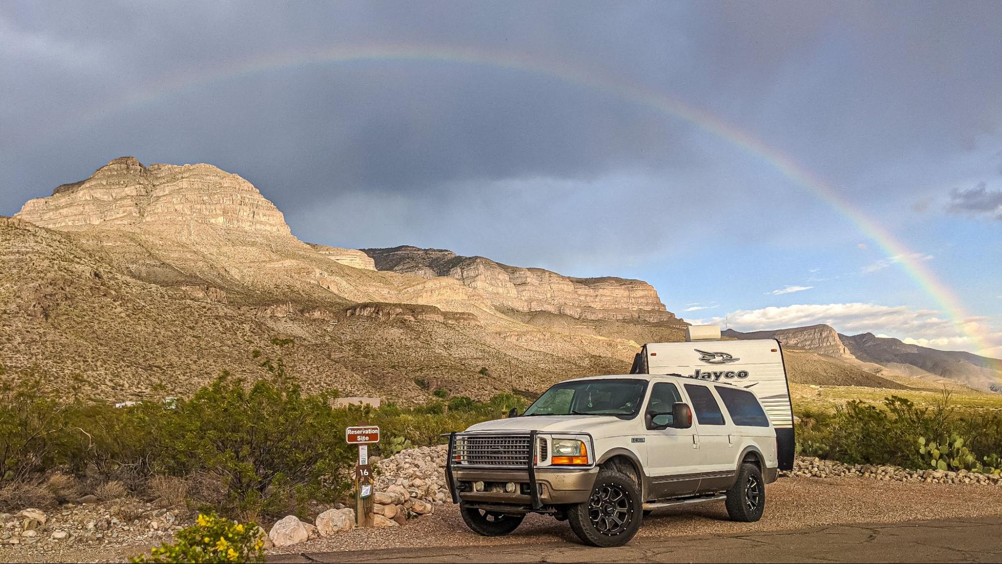 Renee Tilby's Jayco Jay Flight hitched to a large SUV under a rainbow. 