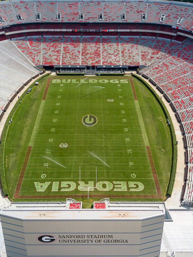 Aerial shot of University of Georgia's Sanford Stadium in Athens, Georgia, home of the Bulldogs, green football field with red seats in white bleachers.