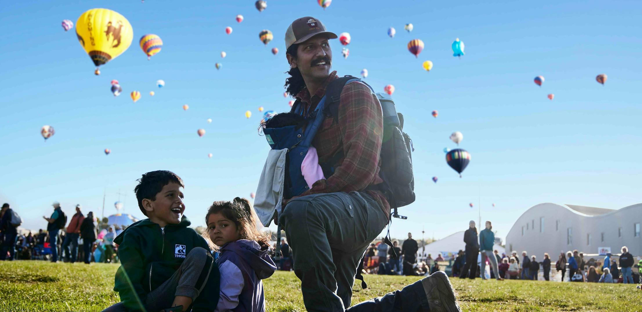 Brian Barton and his kids sitting in the grass at the Albuquerque Balloon Fiesta