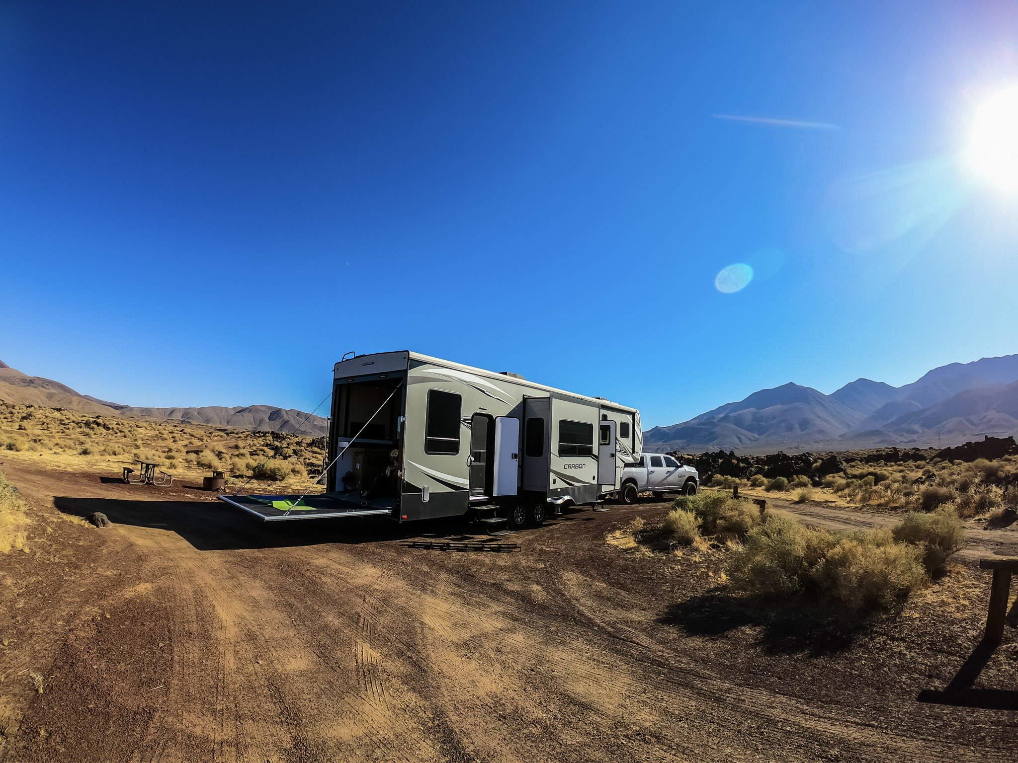 A toy hauler RV parked in the desert under a deep blue sky.