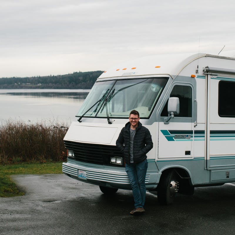 Jeffrey Shipley standing in front of his RV with a lake in the background. 