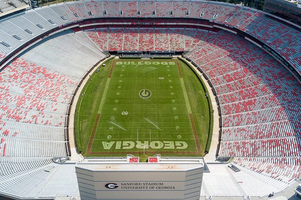 Aerial shot of University of Georgia's Sanford Stadium in Athens, Georgia, home of the Bulldogs, green football field with red seats in white bleachers.