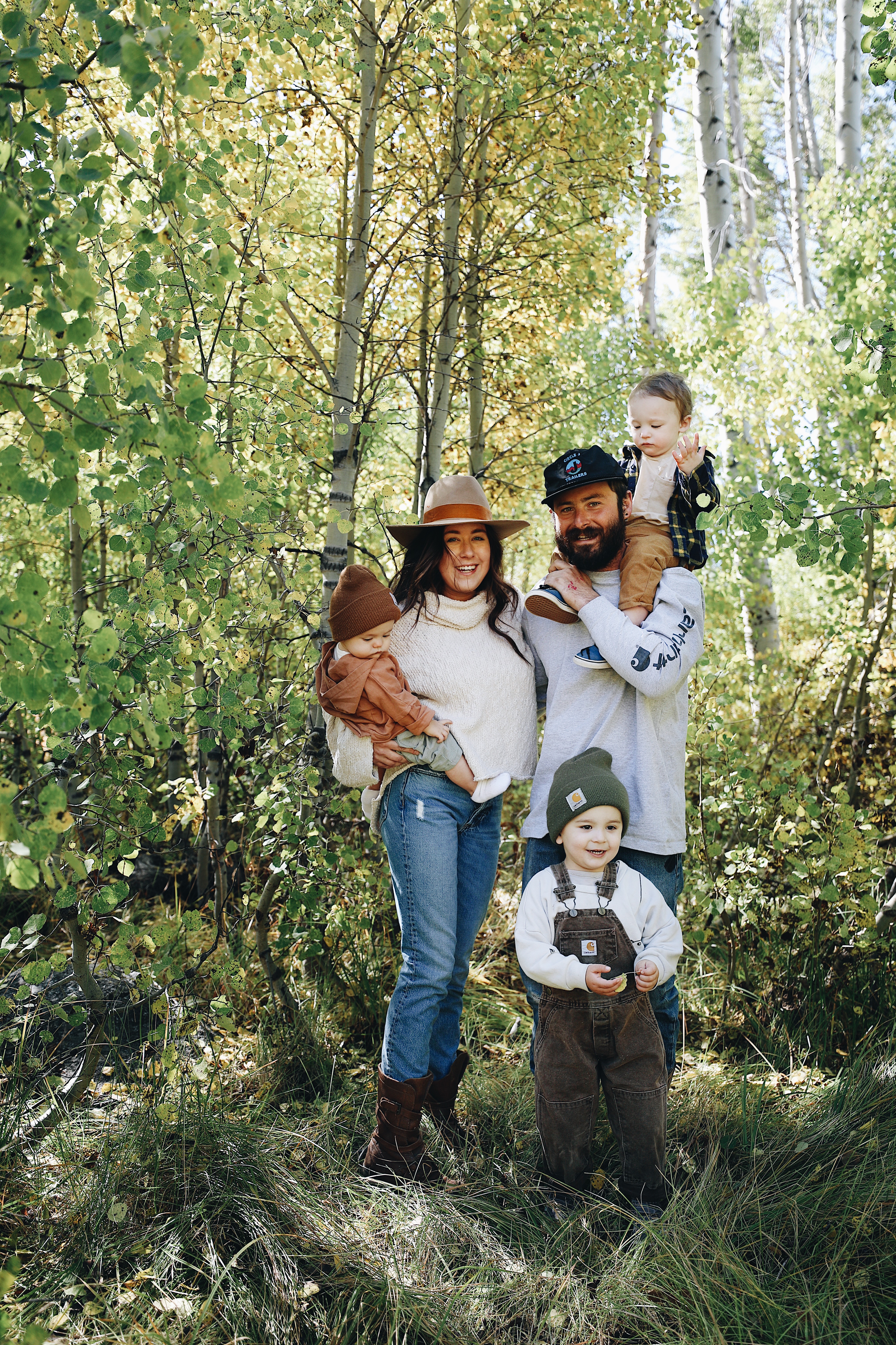 Autumn Bailey with her husband and three kids, posed for a picture amid green trees.