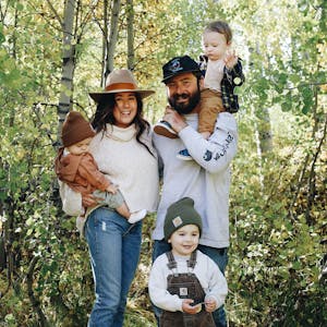Autumn Bailey with her husband and three kids, posed for a picture amid green trees.