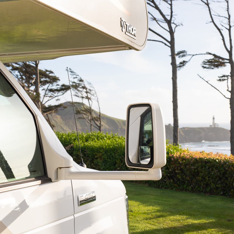 Front view of Class C motorhome looking out over grassy lawn and beach.