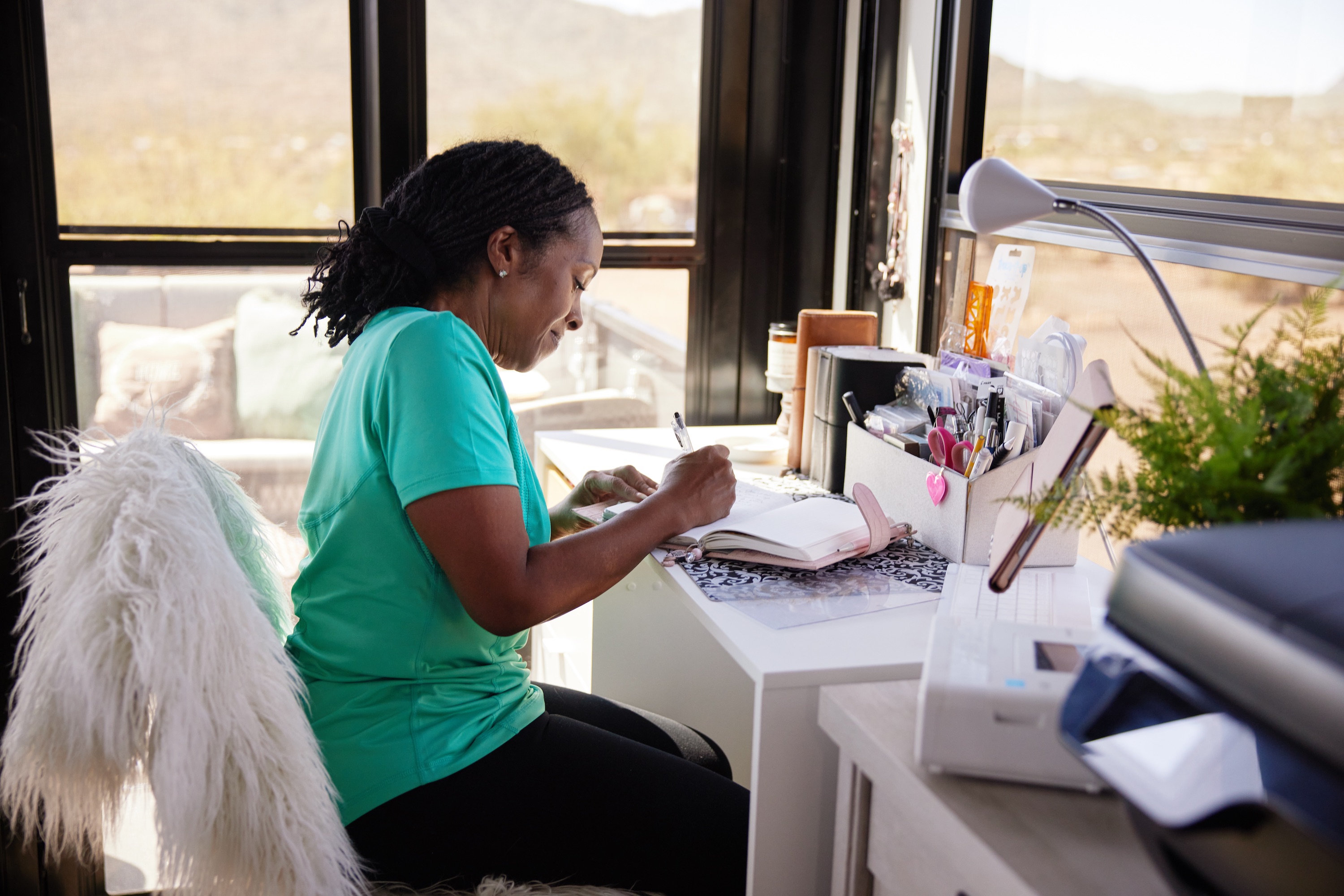 Robin sits at a desk and writes in a journal in the garage of their Keystone Fuzion toy hauler.