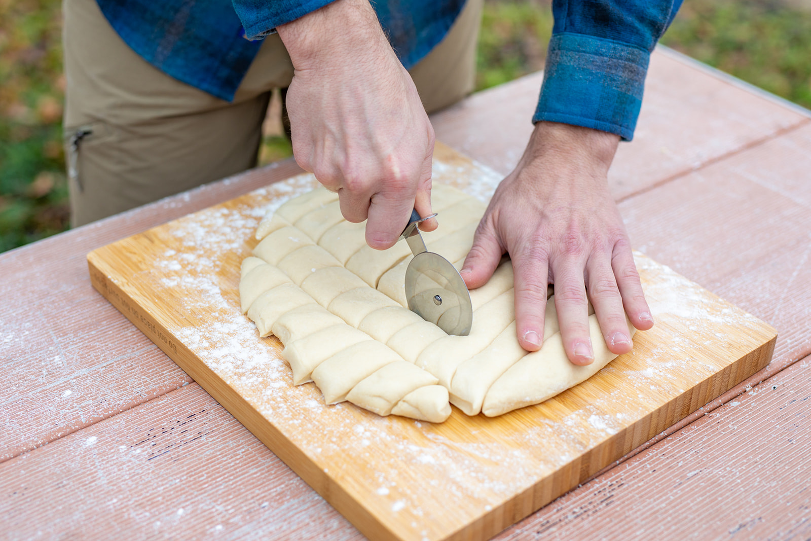 Slicing dough into squares on a cutting board.