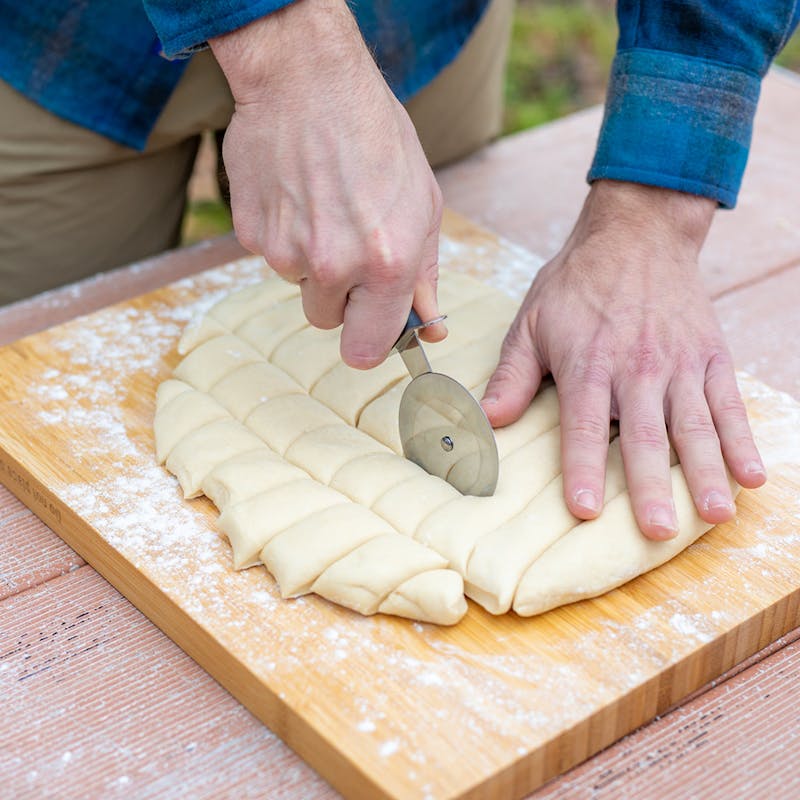 Slicing dough into squares on a cutting board.