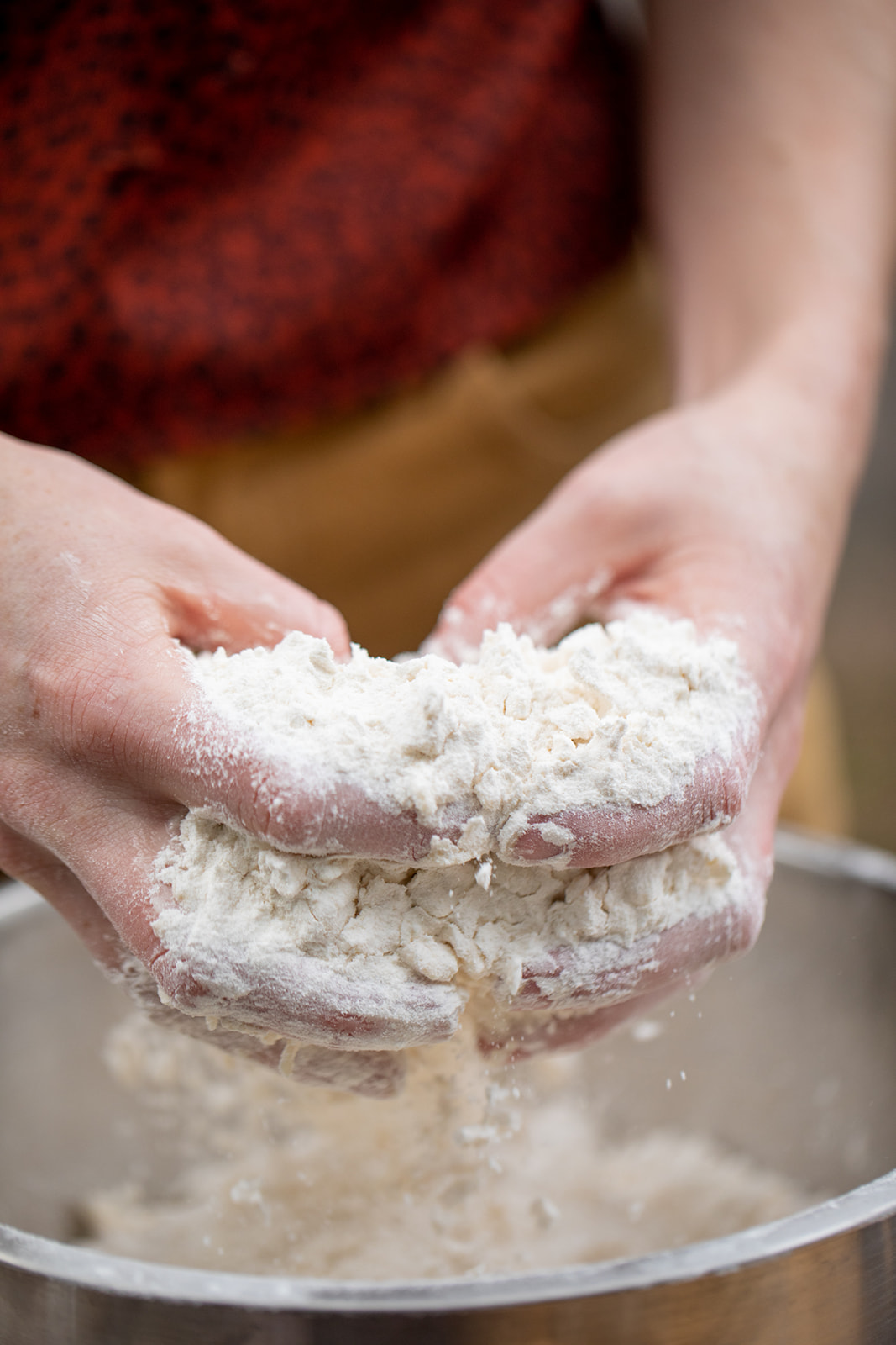 To hands mixing flour and dry ingredients in a bowl. 