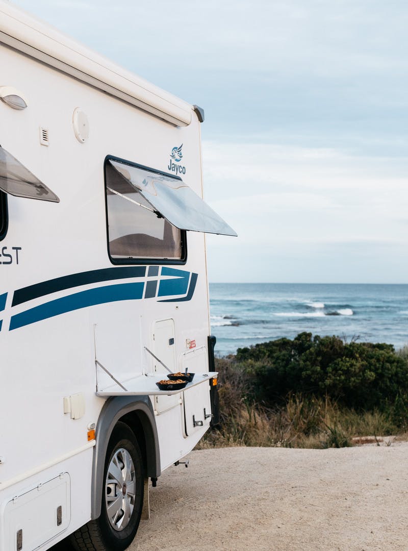 Puddings in skillets on a fold-down tray on the side of a Class C motorhome. In the background, beautiful cloudy sky and ocean waves.