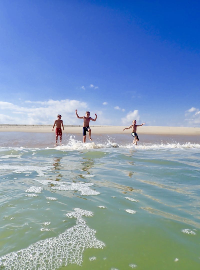 Kids playing on the beach at the ocean.