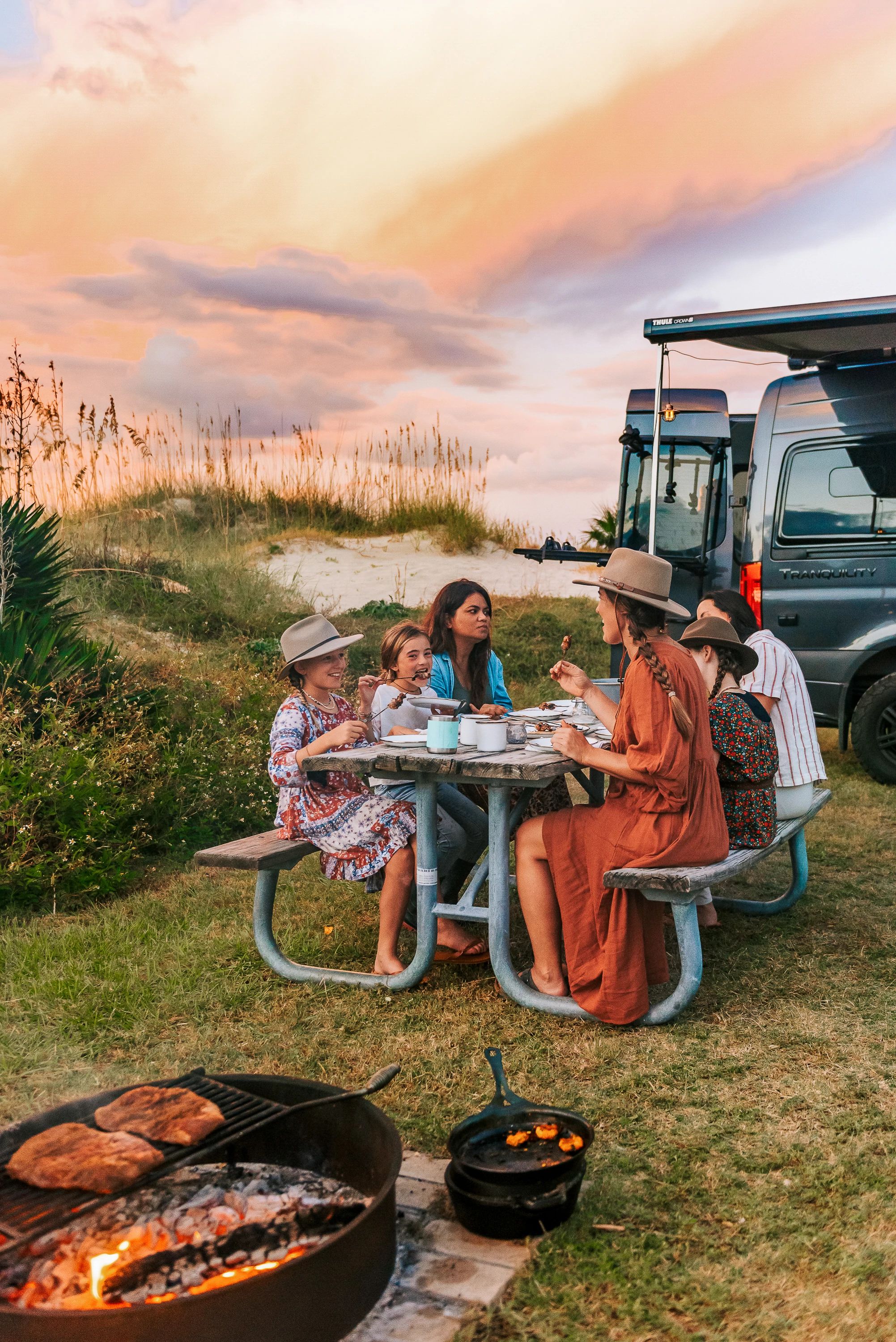 Sarah Glover and a group of friends sitting around a picnic table eating duck skewers