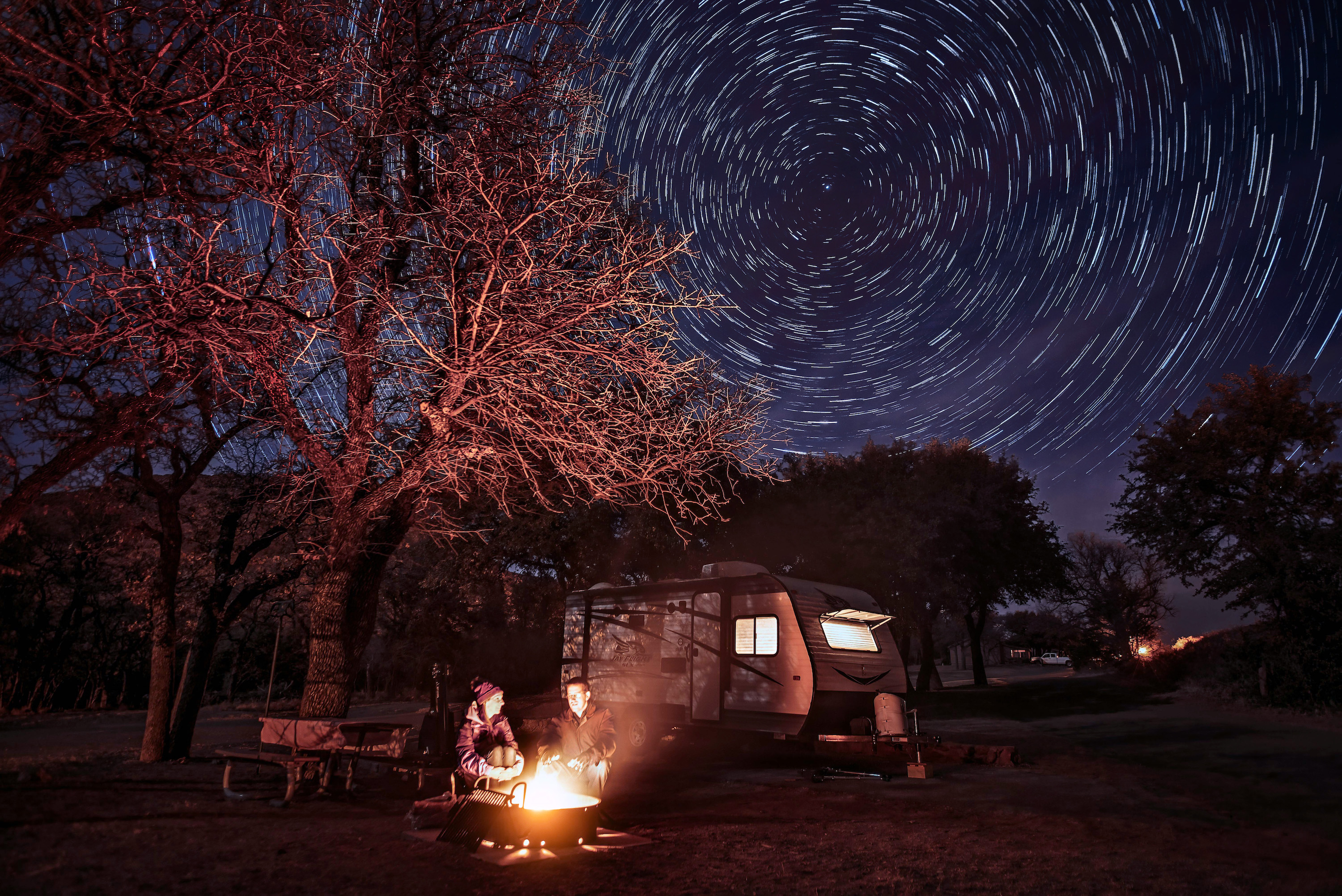 Alison Takacs and her husband around a campfire with a starry sky behind them.