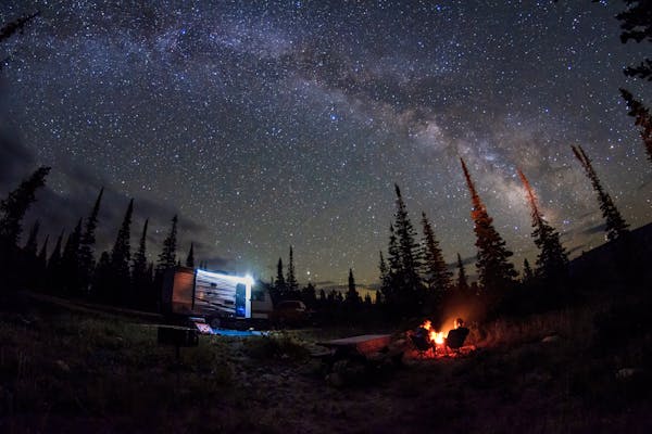 Jason Takacs and his family sitting around a campfire under a starry night sky