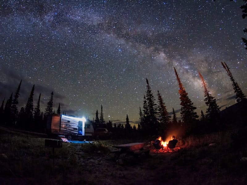Jason Takacs and his family sitting around a campfire under a starry night sky