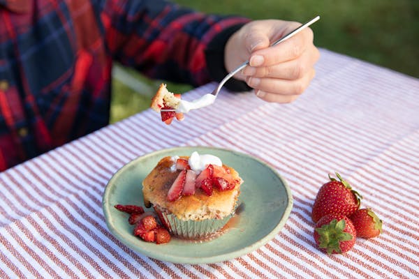 A uses a fork to scoop up a strawberry corn muffin.