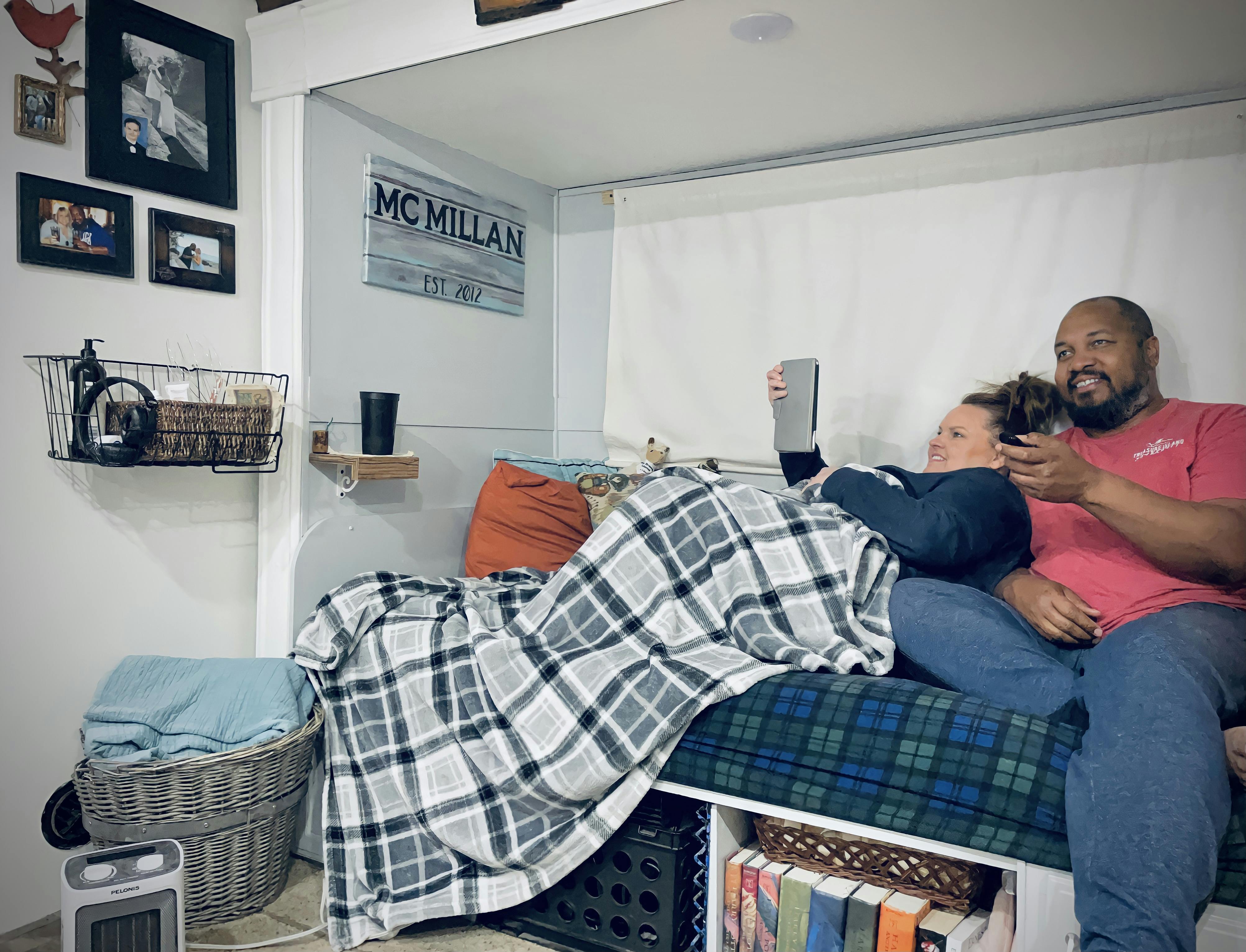 CHRISTINA AND BEN MCMILLAN relaxing inside the living room of their RV