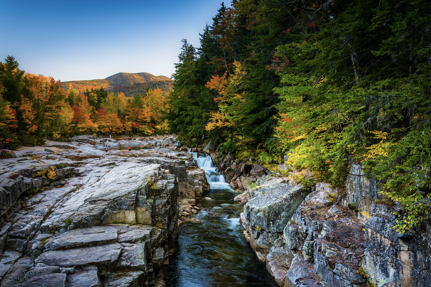 Golden mountains in the distance with small waterfall, surrounded by lush green and orange trees