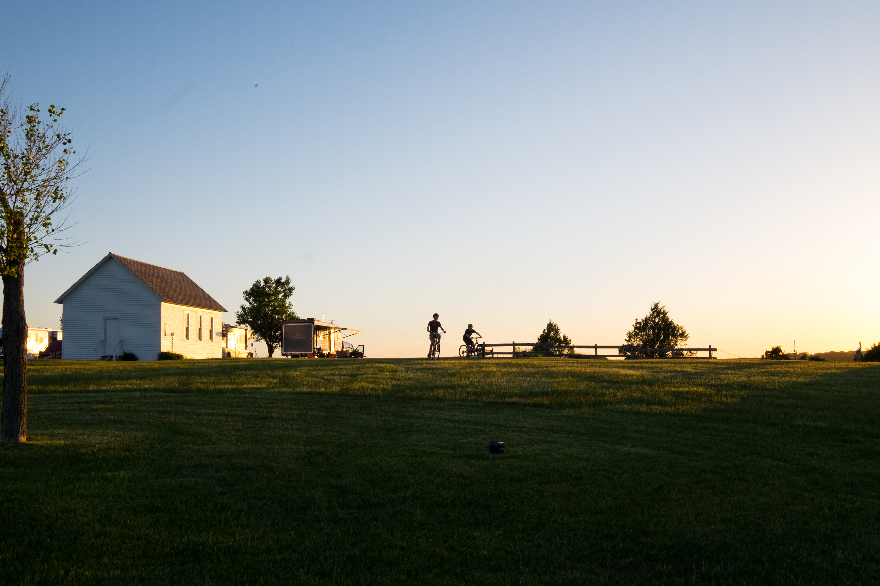 Gretchen Holcomb's kids ride their bikes in a prairie homestead where their RV is parked. 
