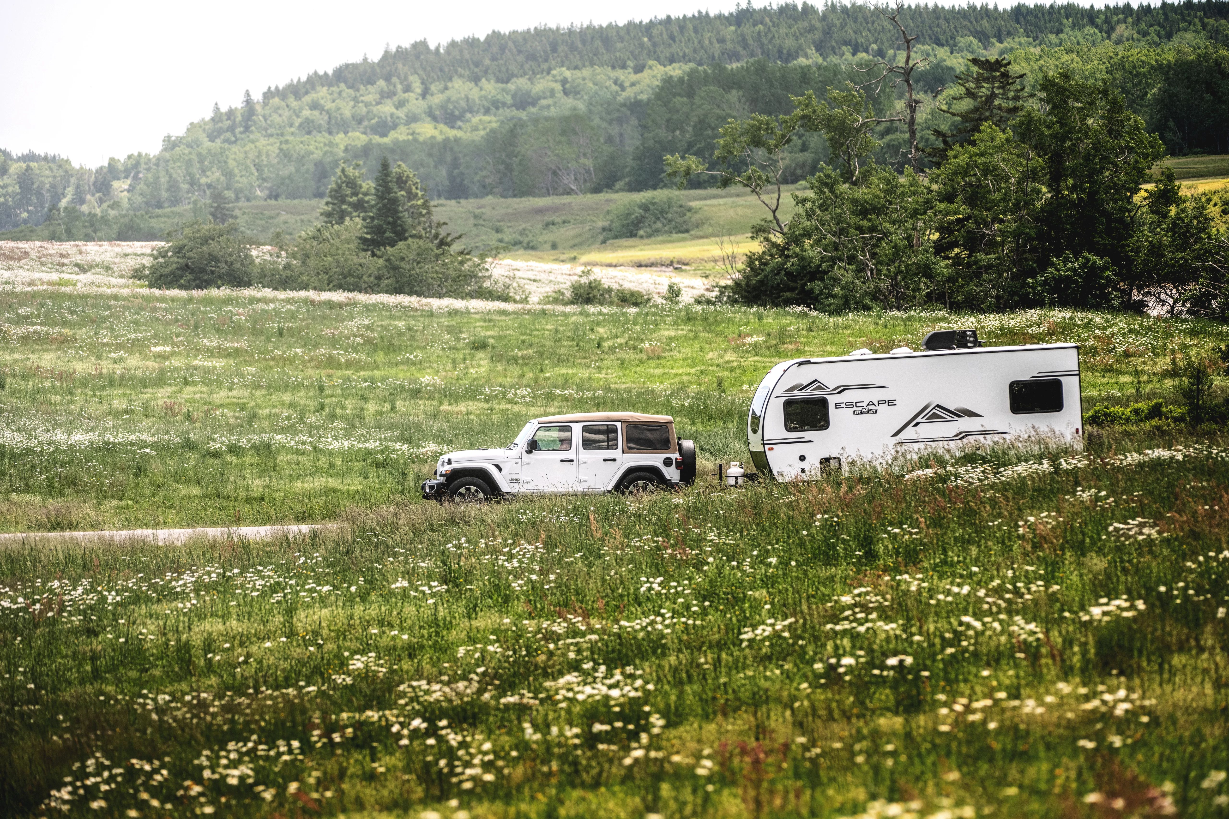 KZ Escape lightweight RV being towed by a Jeep driving down a road 