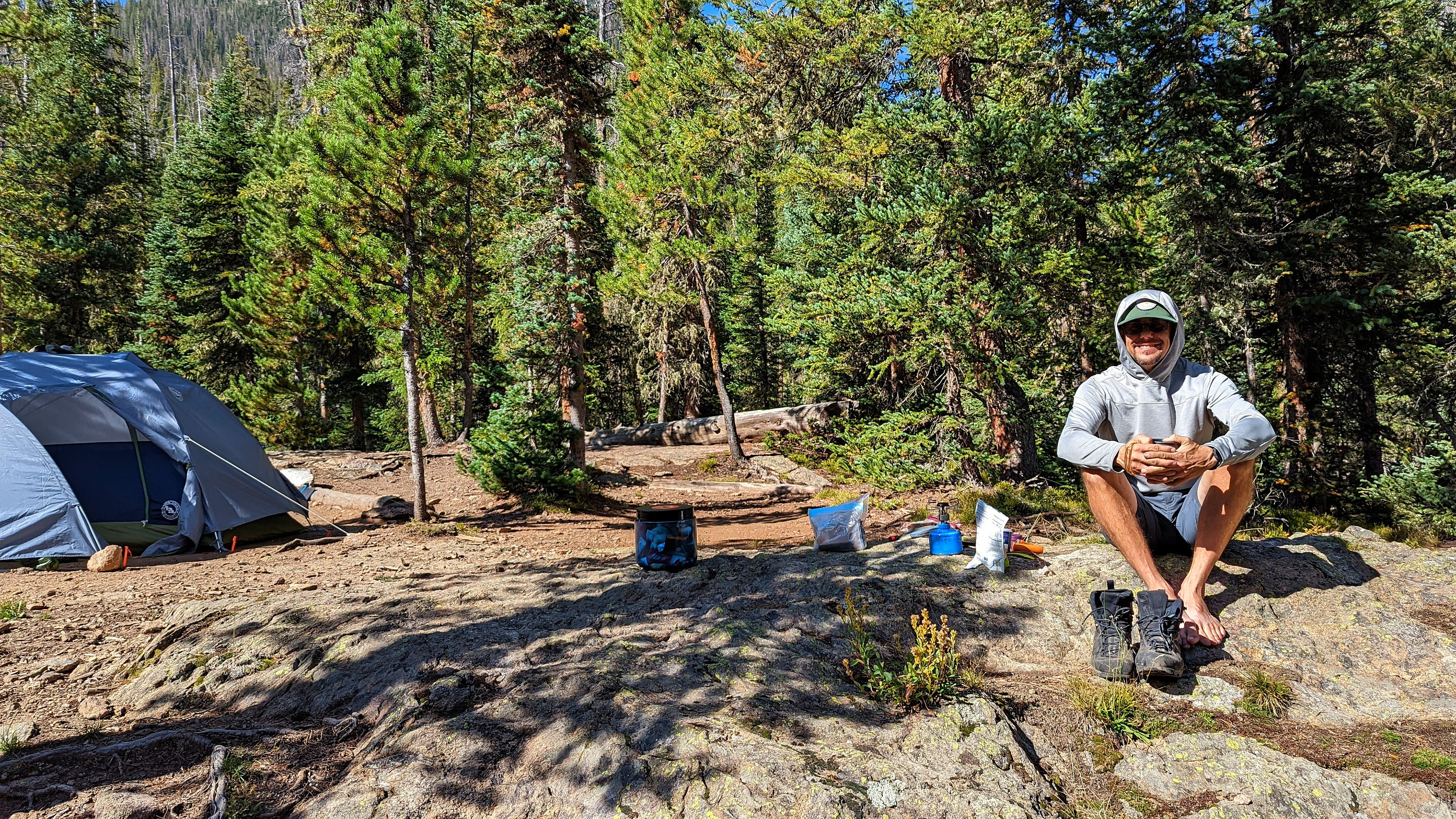 Dustin Bauer sitting on a rock next to his tent