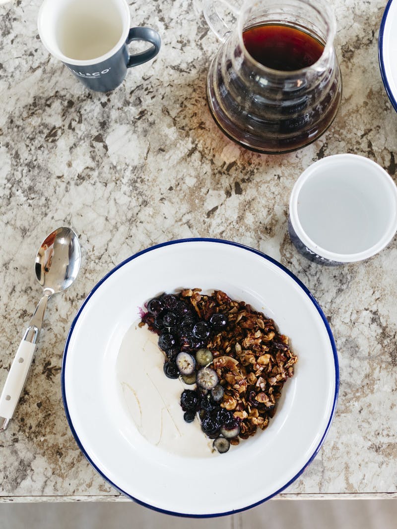 Bowl of hemp granola with blueberries on a tabletop.