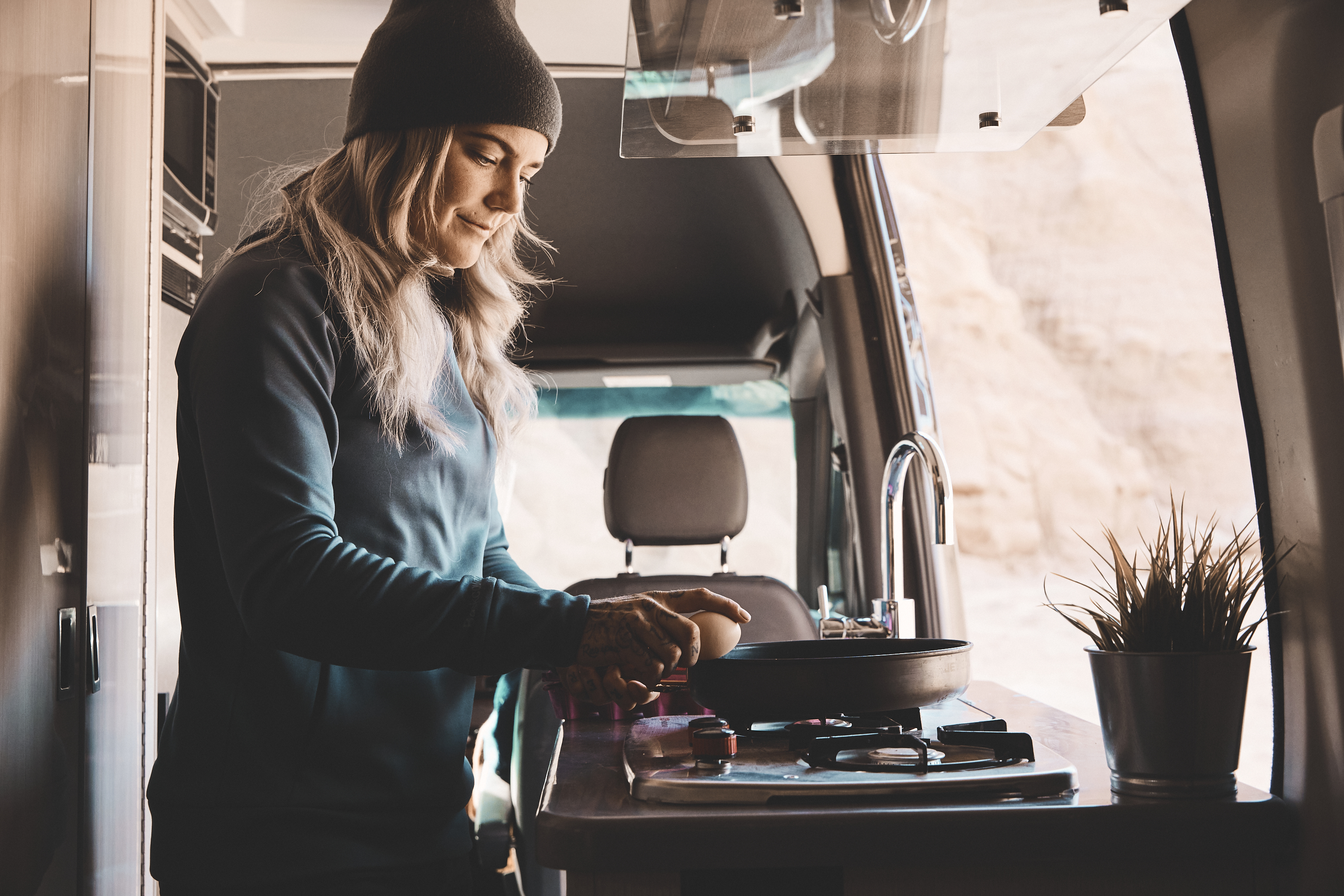 Kalen Thorien cooks breakfast on the stovetop inside her TMC Sanctuary Class B RV.
