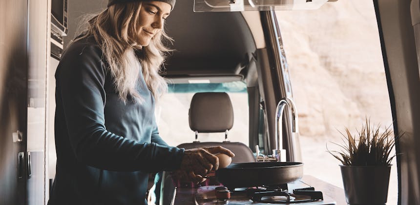 Kalen Thorien cooks breakfast on the stovetop inside her TMC Sanctuary Class B RV.