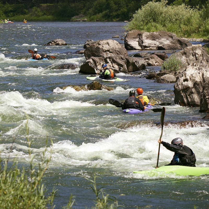 Participants rush down the Blackfoot River in their kayaks.