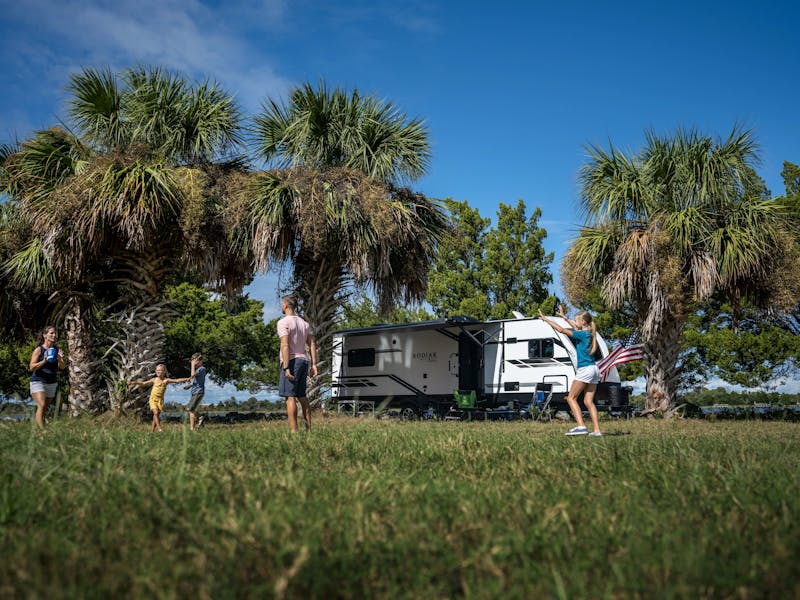 A family plays football near a dutchmen kodiak travel trailer