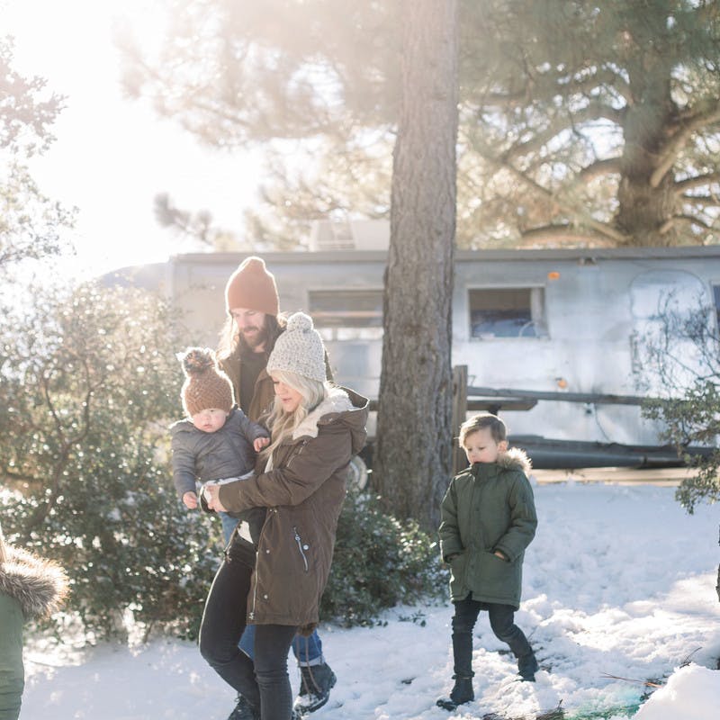 The Thrane family walking in a snowy forest with their Airstream Travel Trailer in the background