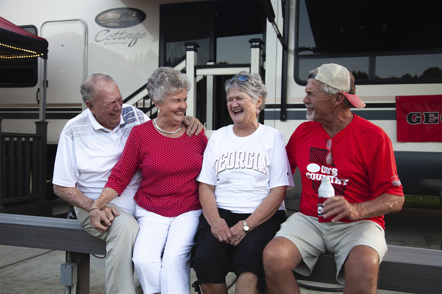 Group of elder friends laughing together in front of RV.