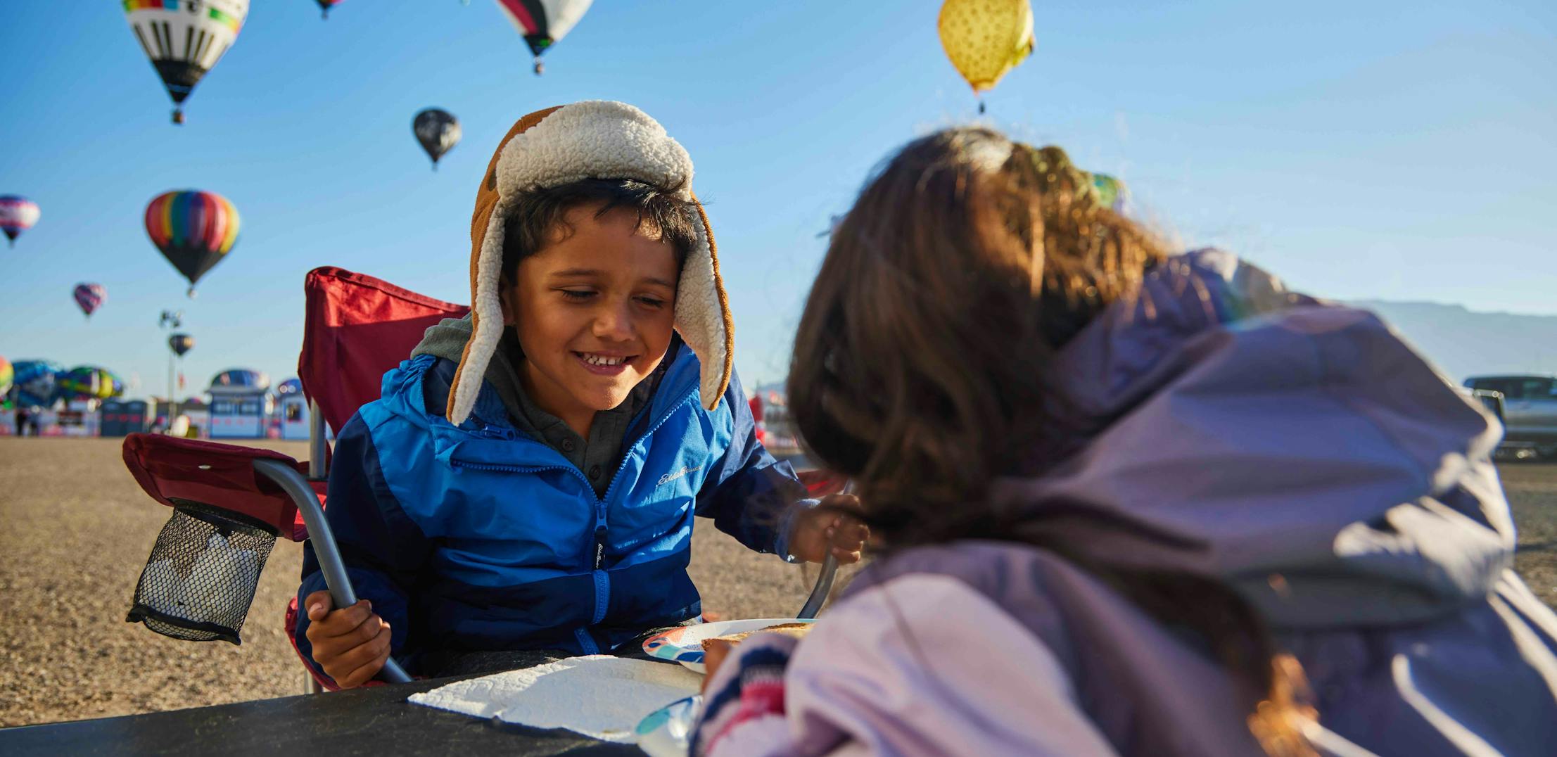 Brian and Surna Barton's kids sitting at a table and eating a snack while at the Albuquerque Balloon Fiesta