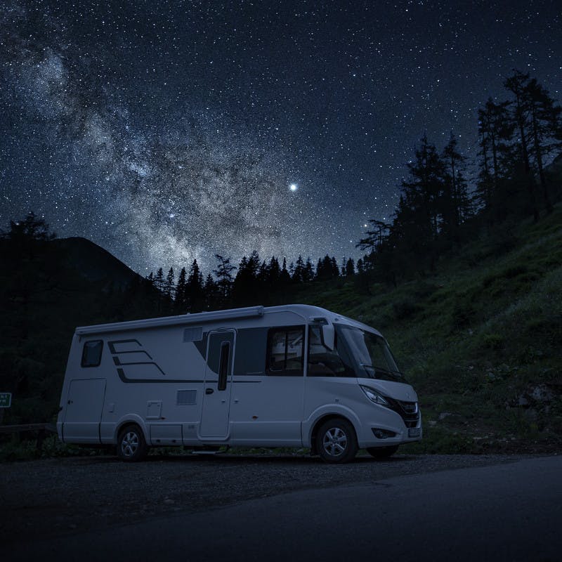 Hymer Class B RV sits underneath the dark, starry sky.